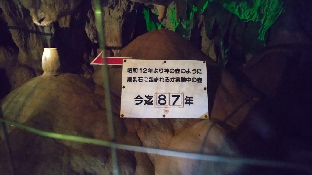 鍾乳石に包まれる土器の実験中を示す案内板（87年経過）