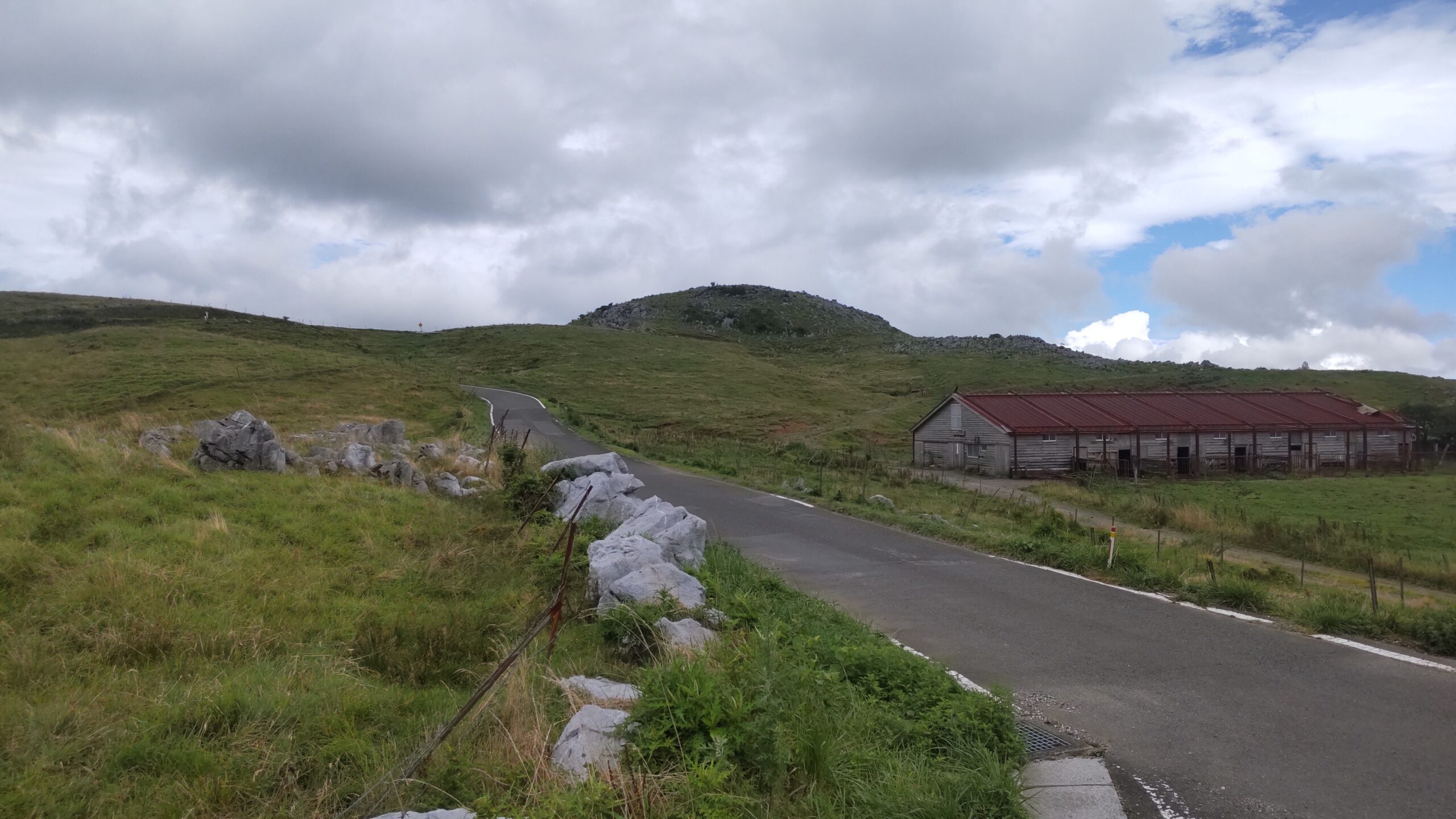 四国カルストの山道と放牧小屋のある風景