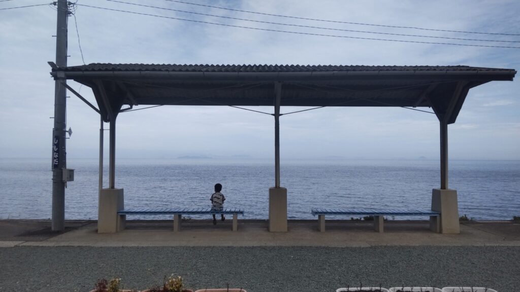 下灘駅のホームで海を眺める人とベンチ