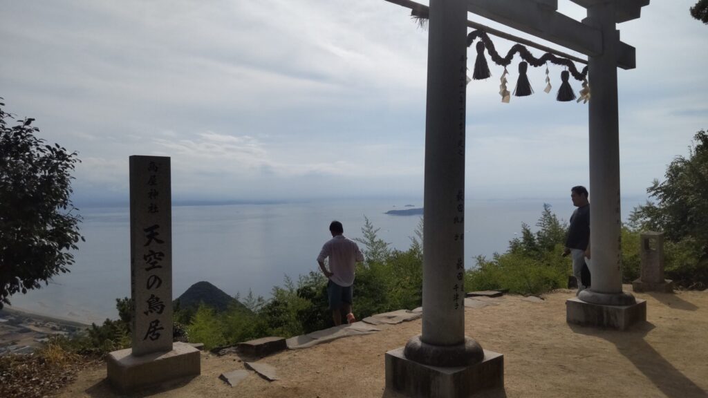 海に向かって立つ高屋神社の鳥居と参拝者